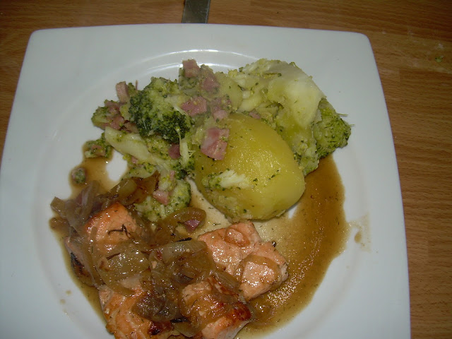 Plato con salmón, puré de patata, patata cocida y brócoli en salsa sobre una mesa de madera